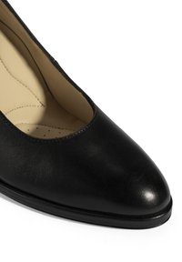 Zwarte leren pump met een ronde neus, een gladde textuur en minimale stiksels. Het interieur heeft een lichtgekleurde voering en bekleding.