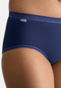Hochgeschnittene marineblaue Unterhose aus glattem, elastischem Stoff mit gewelltem Rand und einem kleinen Etikett am Bund.