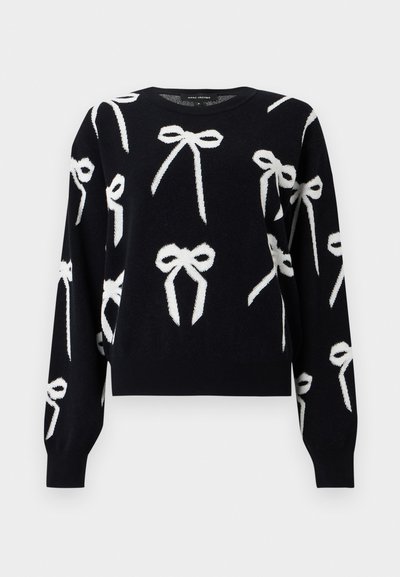 Pull noir à manches longues avec des motifs de nœuds blancs répartis sur le devant, les manches et les épaules, doté d'un col rond et de poignets côtelés.