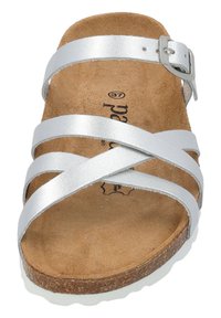 Sandalias plateadas con cuatro tiras entrelazadas, hebilla ajustable y una plantilla de corcho. Textura suave con una suela de goma blanca y plana.