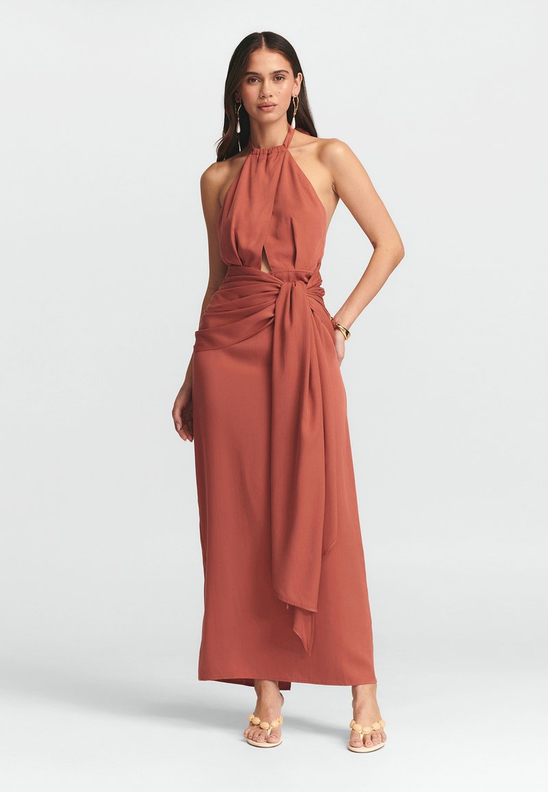 Ruda spalva maxi suknelė su kaklo raišteliu, priekinė raktų formos detalė ir surinkta juosmens dalis su raišteliu. Lygus audinys, plaukiojantis dizainas.