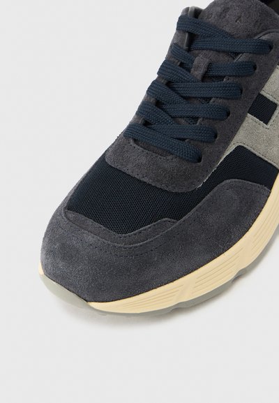 Ναυτικό μπλε σουέντ αθλητικό παπούτσι με διαμερίσματα από δίχτυ, γκρι λεπτομέρειες και επίπεδα κορδόνια. Λαστιχένια σόλα με υφή και μπεζ μεσαία σόλα.