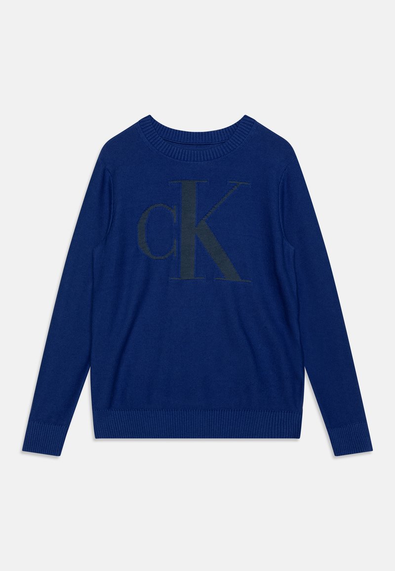 Μπλε πλεκτό πουλόβερ με στρογγυλή λαιμόκοψη και μακρυά μανίκια. Διαθέτει ένα μεγάλο σκούρο πράσινο λογότυπο "cK" μπροστά. Μανίκια και στρίφωμα με ραβδώσεις.
