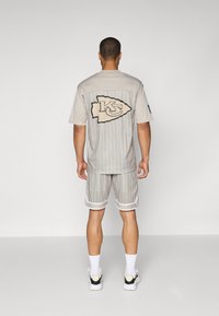 Gray mesh athletic set featuring pinstripes, team logo on back, and white accents. Includes short sleeves and matching shorts.
