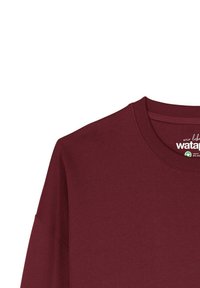 Bordeaux sweatshirt met lange mouwen, ronde halslijn en geribbelde manchetten. Voorzien van een label met de merknaam en details over de biologische certificering.