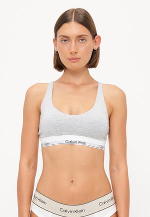 Bralette grigio in cotone con spalline larghe e design supportivo. Presenta un prominente elastico bianco con il marchio "Calvin Klein".