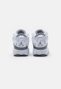 Ett par vita och grå Air Jordan-skor visade från baksidan, med synlig Jumpman-logotyp och dragflikar på en helt vit bakgrund.