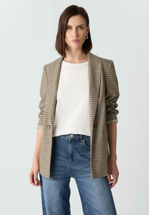 Brown plaid blazer with two buttons, lightweight fabric, and structured shoulders, paired with a white t-shirt and blue jeans.