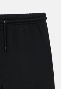 Sorte joggebukser med snøring i livet, mykt stoff, glatt tekstur og et enkelt, minimalistisk design.