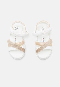 Białe sandały z złotymi akcentami, z krzyżowymi paskami z błyszczącego materiału i miękkim wnętrzem. Rozmiar 22, markowe od Tommy Hilfiger.