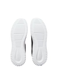 Zapatillas negras con parte superior texturizada en negro y suela de goma blanca. La suela presenta surcos de tracción y un detalle de marca en relieve.