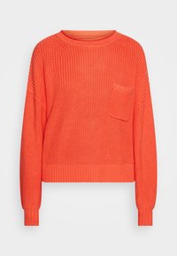 Pletený korálový svetr s volným střihem, kulatým výstřihem a žebrovanými rukávy. Má malou přední kapsu a texturovanou látku.