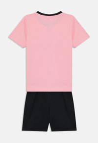 Camiseta de manga corta rosa con cuello negro, combinada con pantalones cortos negros. Ambos artículos cuentan con una textura suave y un diseño sencillo.