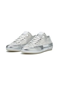 Zapatillas plateadas con un acabado metálico suave, que cuentan con cordones blancos, suelas de goma y un diseño de punta redondeada. Los acentos incluyen un logo en el lateral.