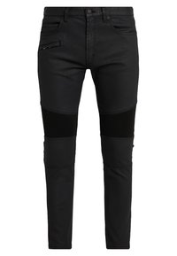 Jeans ajustados negros de mezclilla, con acentos acanalados en las rodillas y un bolsillo con cremallera en la parte frontal. Textura suave, diseño ceñido.