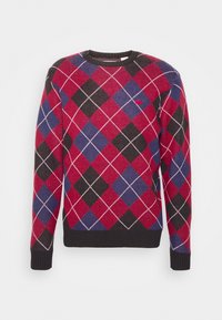 Pull en argyle rouge, noir et bleu avec un col rond et des poignets côtelés. Présente un petit logo à l'avant. Matière en mélange de coton.