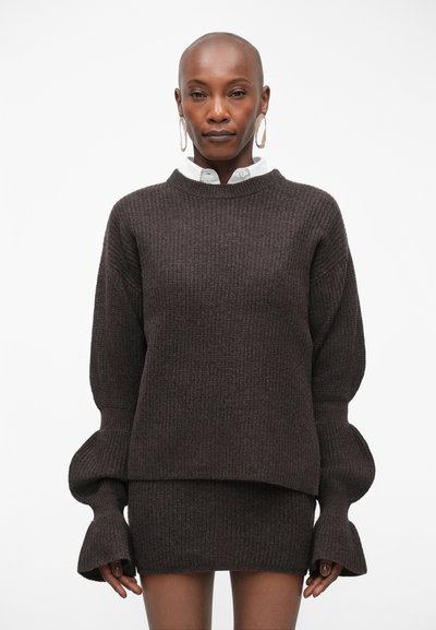 Mørkebrun ribbet sweater med rund halsudskæring og puffede ærmer, parret med en matchende tætsiddende nederdel, der viser et struktureret strikdesign.