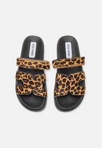 Leopard print slide sandals with two wide straps and a cut-out design. Black sole, textured material, and branding on footbed.