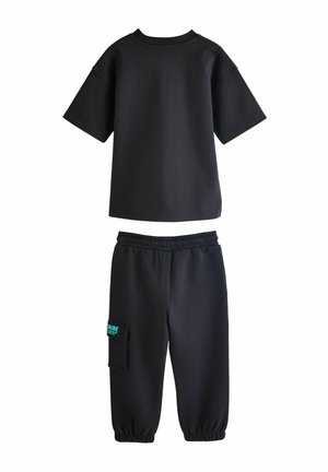 Black short-sleeve t-shirt with a crew neck, paired with black sweatpants featuring an elastic waistband and a side pocket with green lettering.