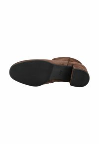 Botte en daim marron avec une semelle en caoutchouc plate. Le dessous présente une surface texturée pour l'adhérence, avec un logo embossé sur la semelle intérieure.