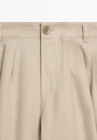 Beige Leinenhose mit Knopfverschluss, Gürtelschlaufen, vorderen Falten und verdecktem Reißverschluss.