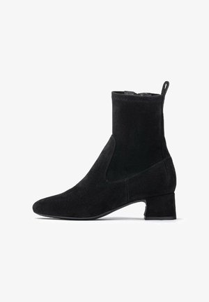 Stivale nero alla caviglia, realizzato in suede, con punta affusolata, tacco a blocco e pannelli laterali elasticizzati per una facile indossabilità. Texture liscia con cuciture sottili.