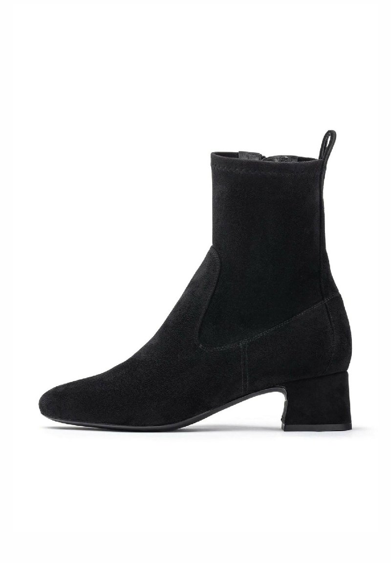 Bottine noire, en daim, avec un bout pointu, un talon bloc et des panneaux latéraux élastiques pour un enfilage facile. Texture lisse avec des coutures subtiles.
