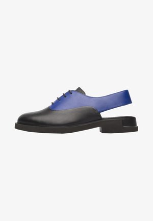Chaussure slingback en cuir noir et bleu avec devant lacé et petit talon bloc, vue de côté sur fond blanc.