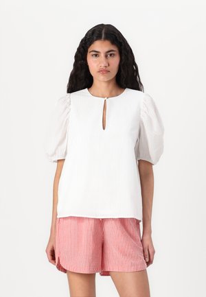 White textured top with puff sleeves and a keyhole neckline, paired with red and white striped shorts.
