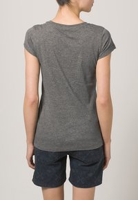 Camiseta gris de manga corta con una textura suave, mostrada por la parte de atrás, combinada con pantalones cortos oscuros con estampado que cuentan con bolsillos.