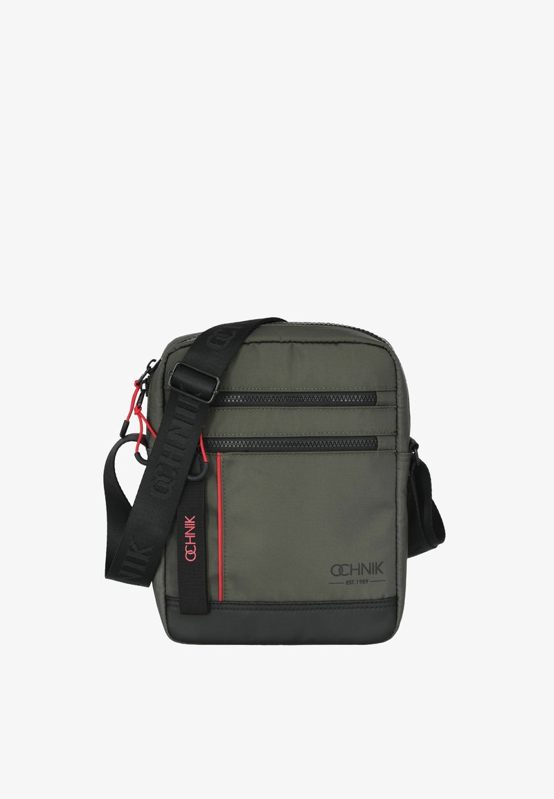 Kompaktowa oliwkowa torba na ramię z czarnymi akcentami, z dwoma zamykanymi kieszeniami i regulowanym paskiem. Teksturowany, trwały materiał.