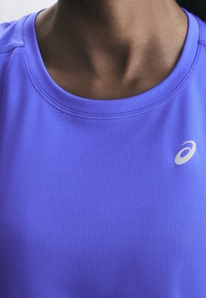 Gros plan d'une personne portant un maillot de sport violet avec un logo Asics blanc sur le côté droit près du col.