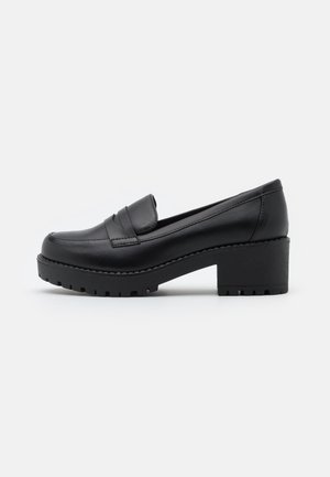 Mocassins en cuir noir avec un petit talon carré, ornés d'un design cousu et d'une semelle texturée pour une meilleure adhérence et stabilité.