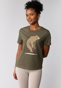 Olijfgroene t-shirt met een afbeelding van een beer die op een rode fiets rijdt. Korte mouwen, ronde halslijn, gemaakt van zachte katoen.