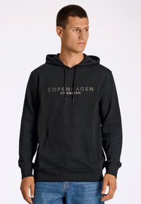 Sudadera negra con bolsillo frontal, capucha con cordón y texto "Copenhague" en gris. Fabricada en un tejido suave y de textura lisa.
