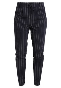 Granatowe spodnie z białymi pionowymi paskami, elastyczny pas, sznurek do regulacji oraz boczne kieszenie. Wykonane z miękkiego, strukturalnego materiału.