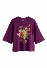 Lila Kurzarm-Sweatshirt mit einer Süßigkeiten-Grafik und dem Text: "Was ist dein Favorit?" in Gold. Weicher Stoff und lockere Passform.