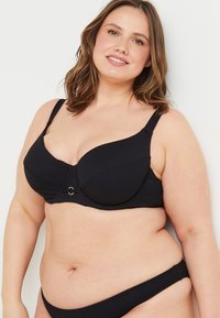 Reggiseno nero con sottoseno a ripresa, spalline larghe e un accento dorato al centro. Design classico adatto per supporto e comfort.