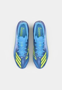 Blue soccer shoes with a sleek design, featuring yellow accents, textured surface, and laces. "Messi" logo visible on the tongue.