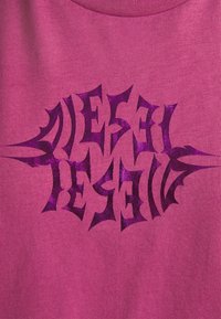 Fuchsiasträng t-shirt i bomull med fet, mörklila grafisk text med skarpa kanter och glänsande finish, centrerad på framsidan.