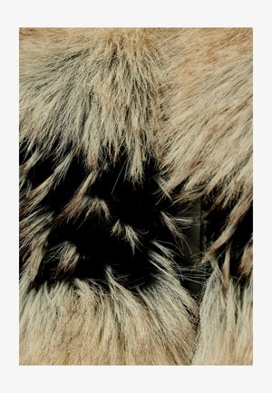 Materiale in pelliccia sintetica beige e nera, caratterizzato da fili lunghi e leggeri. La texture appare morbida, con un aspetto stratificato che mette in evidenza il contrasto.