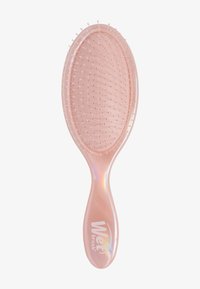 Roze ovale haarborstel met een doorzichtige handgreep, flexibele haren en een gestructureerd oppervlak. Voorzien van het "Wet Brush"-logo in het wit.