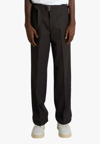 Pantaloni marrone scuro a vita alta con cintura, design a gamba dritta e fronte piatto, abbinati a sneakers bianche. Texture liscia.