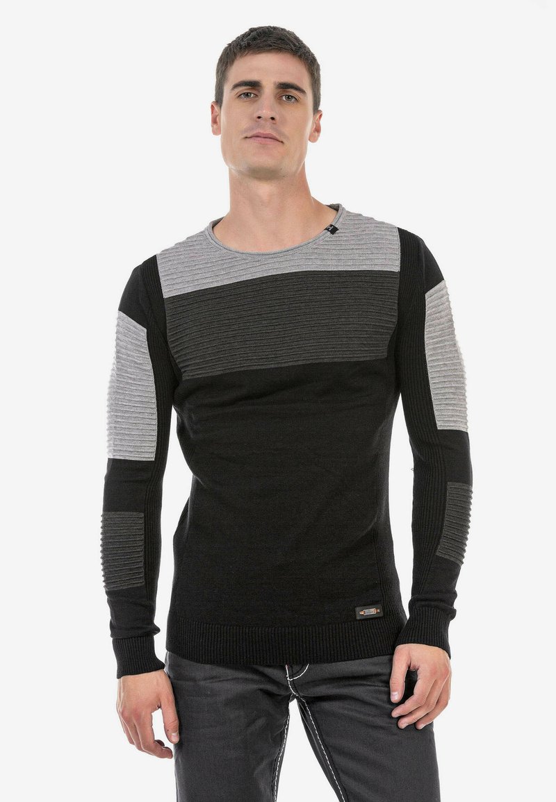 Schwarzer und grauer gerippter Pullover mit Rundhalsausschnitt und langen Ärmeln, der strukturierte Akzente an den Schultern und Ärmeln aufweist.