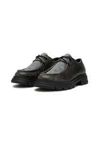 Des chaussures noires et grises avec un matériau supérieur texturé, un design à lacets et une semelle en caoutchouc robuste, présentant une finition lisse et une forme incurvée.