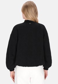 Sudadera negra con acabado texturizado, cuello alto y puños y dobladillo elásticos. Presenta un detalle de botón en la parte trasera.