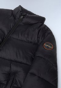 Sort puffjakke med høj krave, lynlås og et rund logo patch på ærmet. Glat, skinnende tekstur med kviltede sektioner.