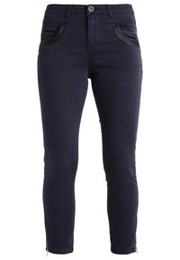 Jeans ajustados de color azul marino, confeccionados en una mezcla de algodón, con detalles de cuero sintético en los bolsillos y cremalleras en el dobladillo, con un diseño entallado.