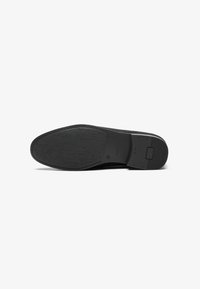 Schwarze Schuhsohle mit strukturiertem Gummioberfläche, die einen glatten Zehen- und Fersenbereich sowie abgerundete Kanten für ergonomisches Design aufweist.