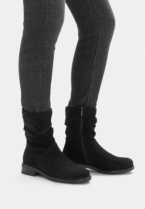 Schwarze Wildleder-Stiefeletten mit lässigem Design, seitlichem Reißverschluss und niedrigem, gestapeltem Absatz. Obermaterial mit Struktur und glattes Innenfutter.